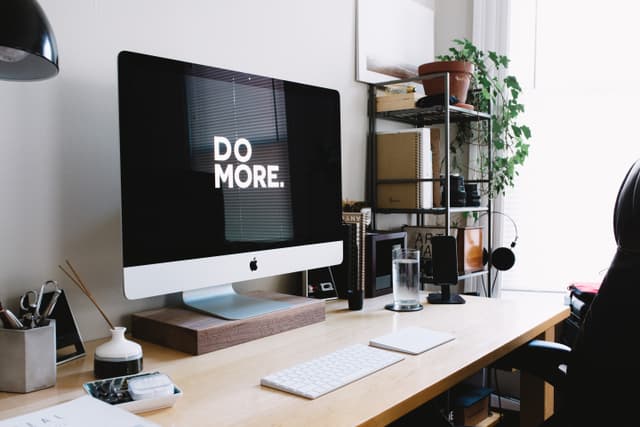 Desk with Mac computer that says 'Do More.'